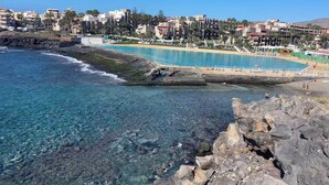 Un complejo turístico frente al mar, con aguas azul turquesa, un litoral rocoso y una playa de arena.