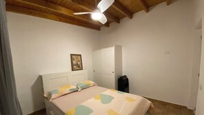 Un dormitorio con cama, ventilador de techo, armario y espejo.