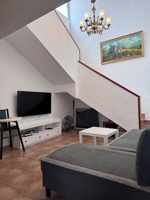 A living room with a TV, a sofa, a dining table, and a staircase. - Family 3BR Townhouse Pool Terrace South Tenerife (Arona)