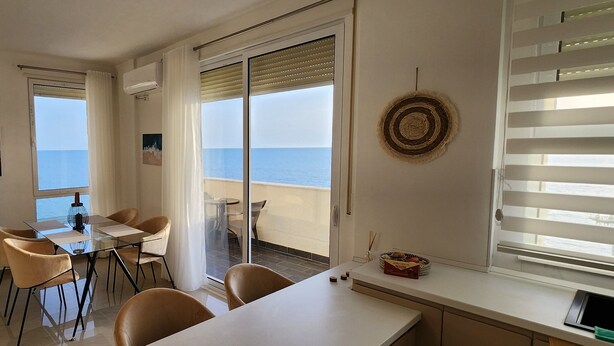 A modern living room with a dining area, large windows with ocean views, and a balcony. - Experience a fantastic stay at Dolce Vita apartment, right next to the beach! (Durrës)