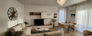 Ein modernes Wohnzimmer mit Sofa, Couchtisch, Fernseher und Essbereich.