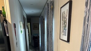 A hallway with a potted plant, wooden flooring, and framed pictures on the walls. - Nature At the Cozy House (Slidell)