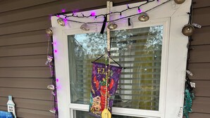 A porch with a turquoise table, wicker chair, and a hanging decoration with 'Happy Mardi Gras' text. - Nature At the Cozy House (Slidell)