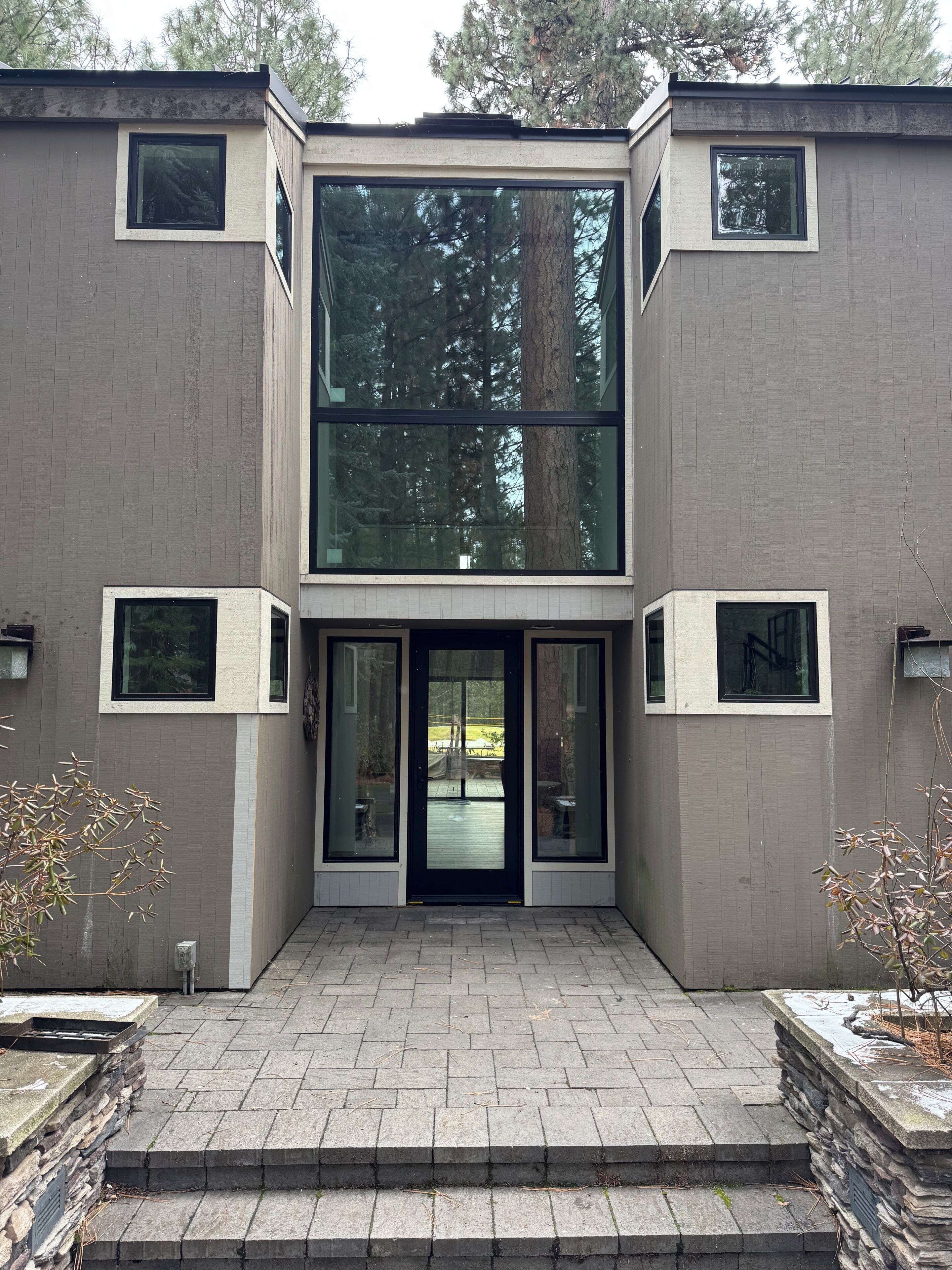 A modern building with a symmetrical facade, large glass windows, and a central entrance with a door.