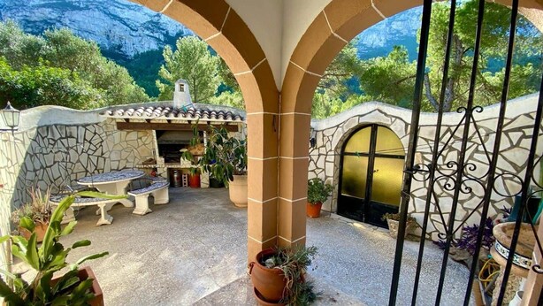 An outdoor patio with stone walls, a stone fireplace, and potted plants. - Casa Estrella - Natural Mountain Retreat (Dénia)