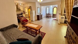 A living room with a sofa, a coffee table, and a dining area with chairs and a table. There is a kitchen area with a refrigerator and a microwave. - Casa Estrella - Natural Mountain Retreat (Dénia)