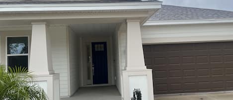 Una casa residencial con porche cubierto, garaje y entrada para vehículos.