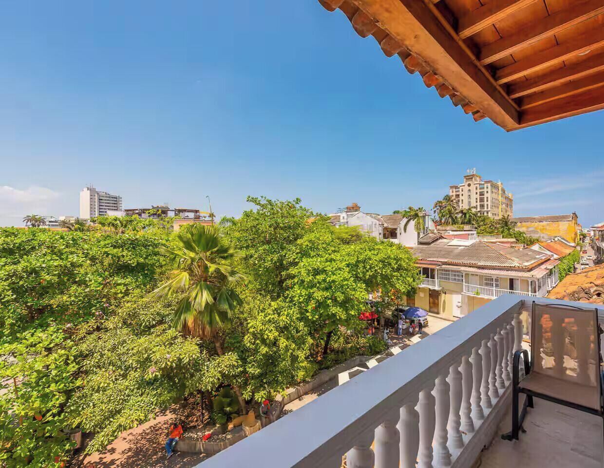 Un balcón con vistas a una zona verde exuberante y edificios al fondo.