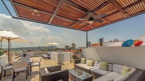 Une terrasse extérieure avec des sièges, un ventilateur de plafond et une vue sur la ville.