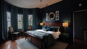 A bedroom with a large bed, a chair, a small table, and a mirror on the wall. - 4 Bedrooms/Hot Tub/3 Parking Spaces/Luxury (Savannah)