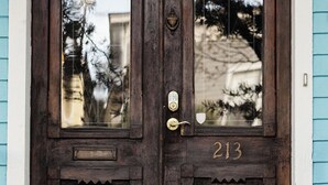 A dark wooden door with the number 213, a brass doorknob, and a glass panel reflecting trees. - 4 Bedrooms/Hot Tub/3 Parking Spaces/Luxury (Savannah)