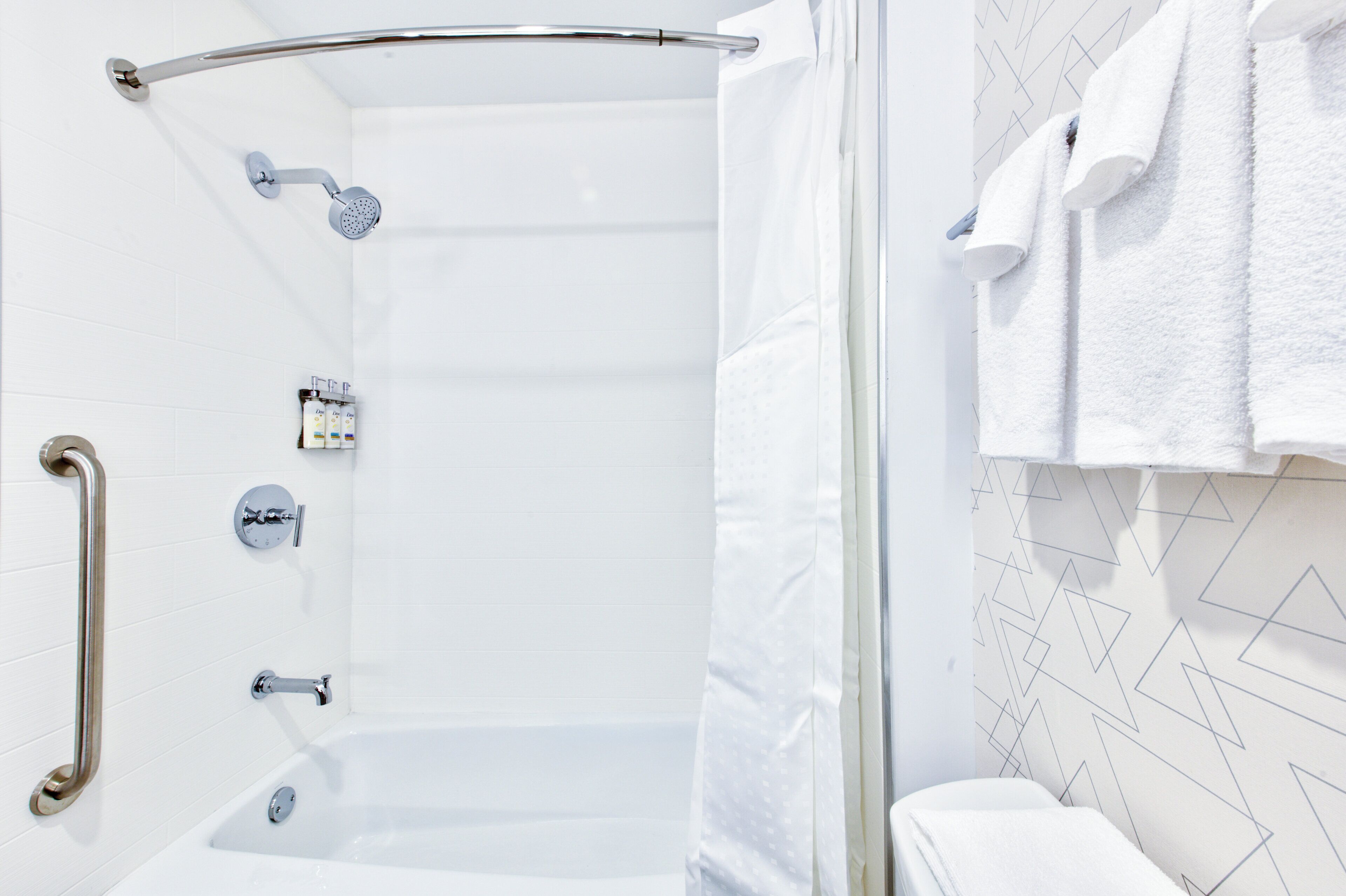A modern bathroom with a walk-in shower, grab bars, and a towel rack.