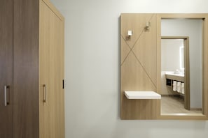 Ein Badezimmer mit einem Holzkosmetikschrank, einem Spiegel und einem Handtuchhalter.
