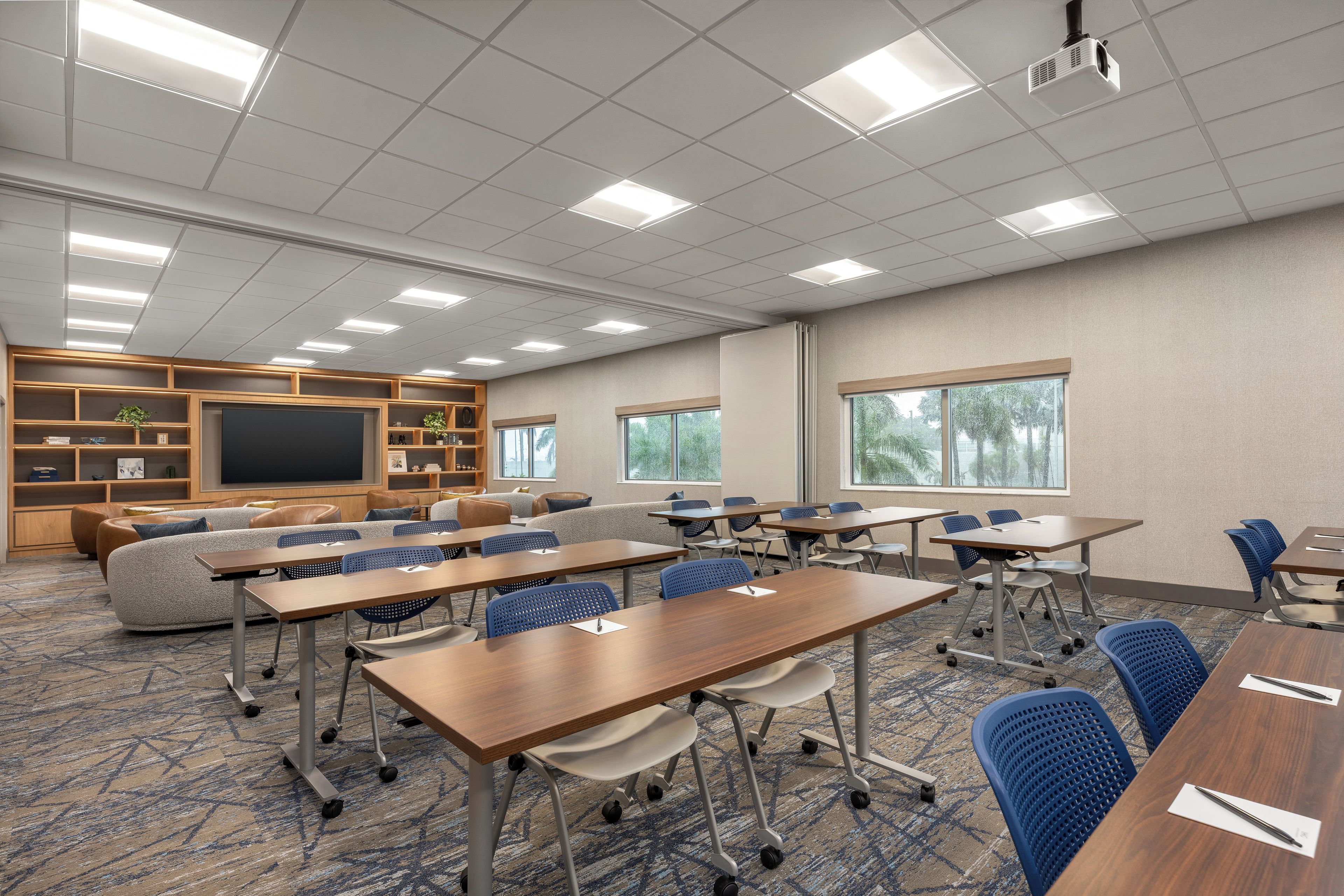 A conference room with tables, chairs, a projector, and a blackboard.