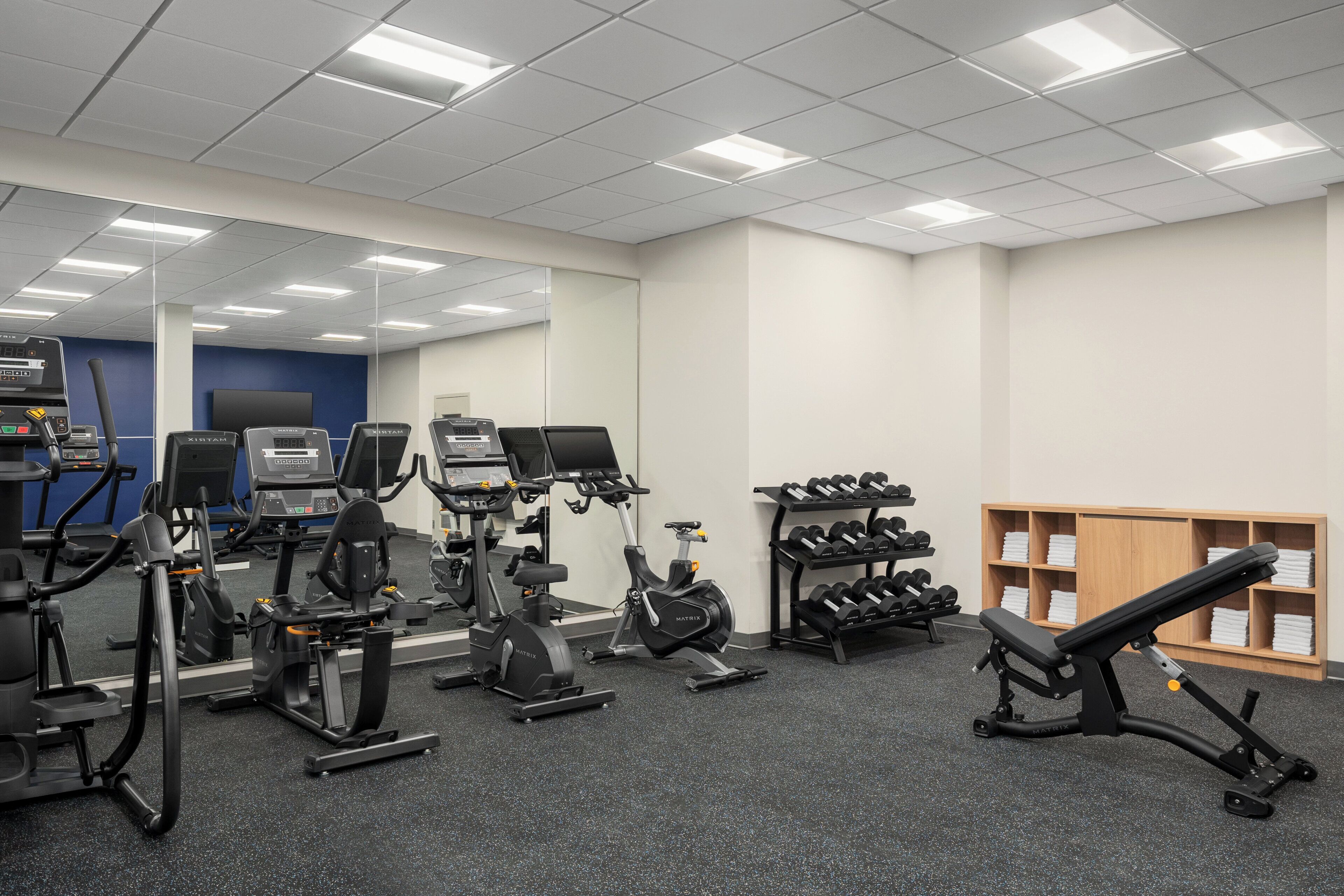 A gym with various exercise equipment, including treadmills, stationary bikes, and dumbbells.