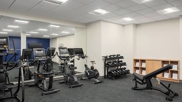 A gym with various exercise equipment, including treadmills, stationary bikes, and dumbbells.
