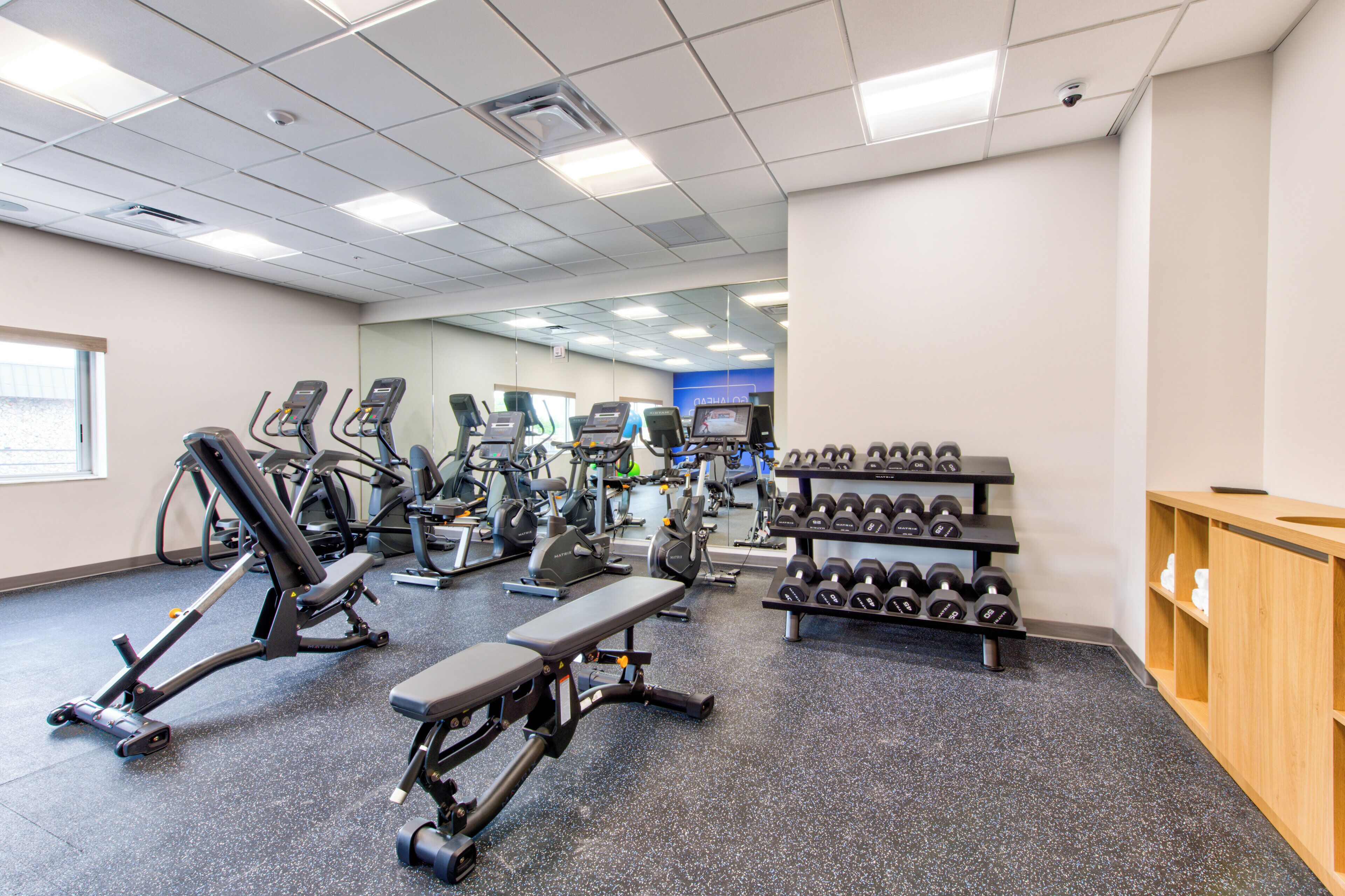 A gym with various exercise equipment, including treadmills, elliptical machines, and dumbbells.