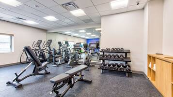 A gym with various exercise equipment, including treadmills, elliptical machines, and dumbbells.