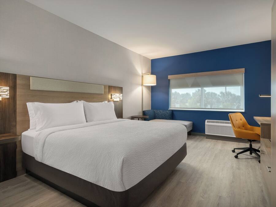 Een moderne hotelkamer met een groot bed, een bureau, een stoel en een raam met uitzicht.