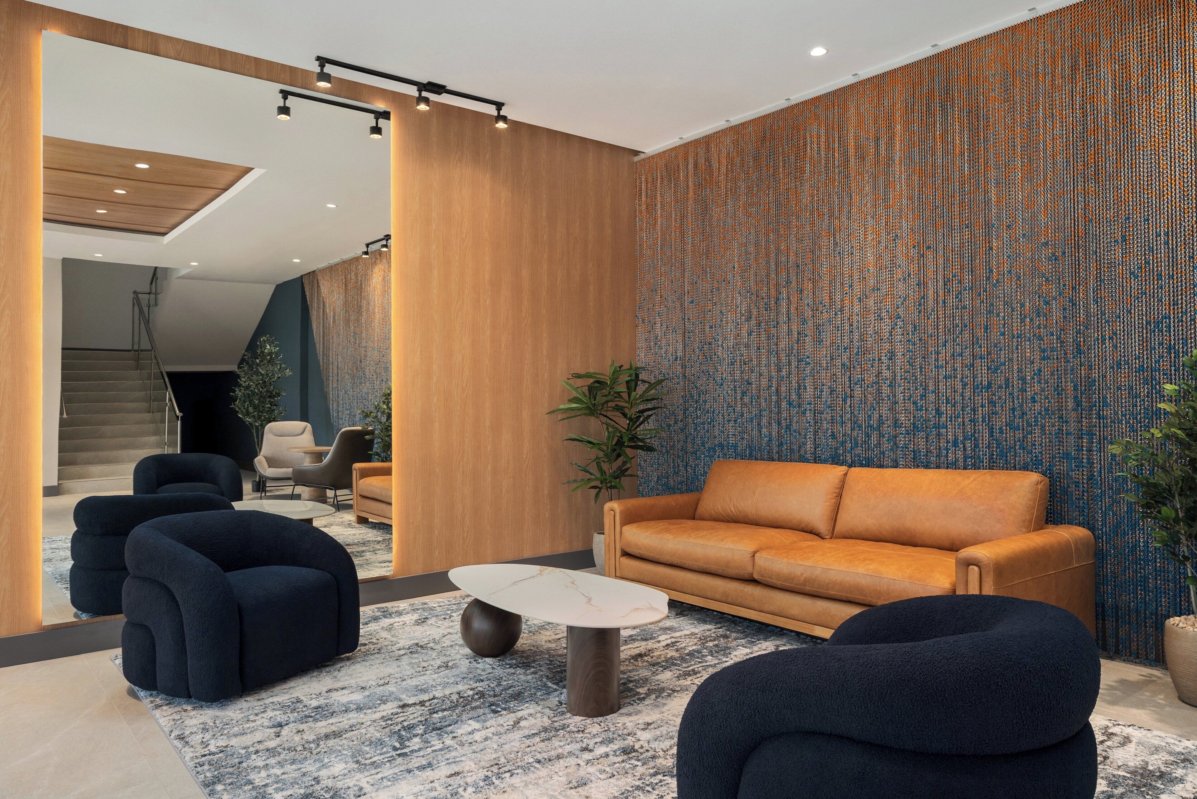 Un salon moderne avec un canapé, des fauteuils, une table basse et un mur décoré de motifs.