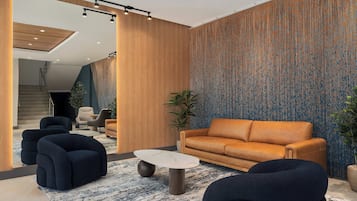 Un salon moderne avec un canapé, des fauteuils, une table basse et un mur décoré de motifs.