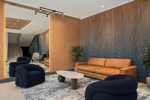A modern living room with a sofa, armchairs, a coffee table, and a patterned wall. - Holiday Inn Express & Suites Miami Intl Airport - 36th St (Miami)