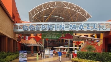 The Dolphin Mall entrance with a large sign, escalators, and a covered area with flags.