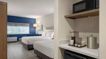 Ein Hotelzimmer mit zwei Betten, einer Mikrowelle, einer Kaffeemaschine und einem Mülleimer.