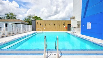 A swimming pool with a wooden wall and a blue building in the background.