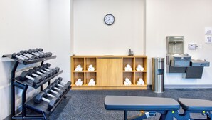 A gym with exercise equipment, a clock, and a water station. - Holiday Inn Express & Suites Miami Intl Airport - 36th St (Miami)