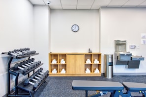 Un gimnasio con equipo de ejercicio, un reloj y una estación de agua.
