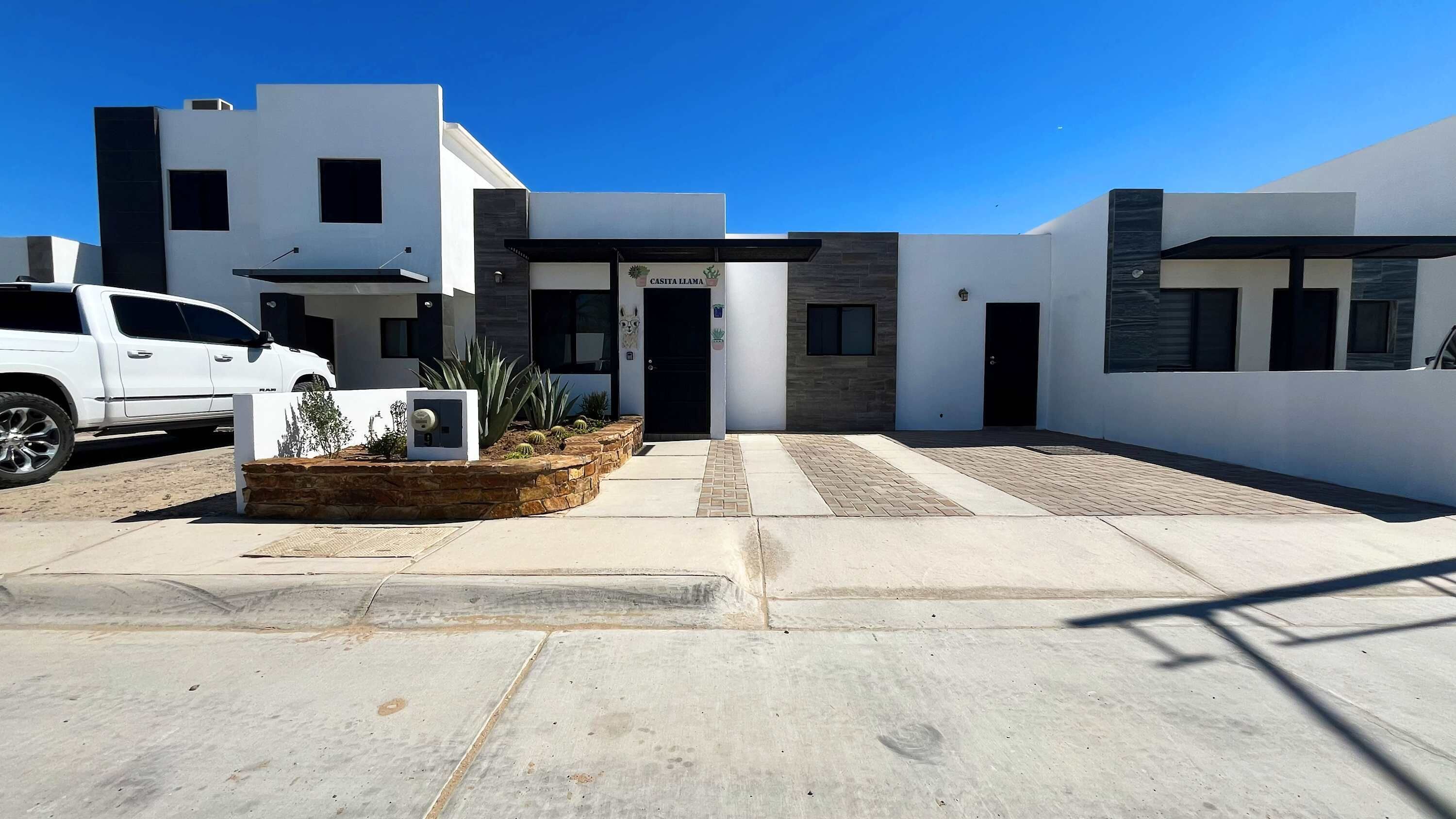 A modern building with a flat roof, a central entrance, and a sign reading 'CASITA LLAMA'.
