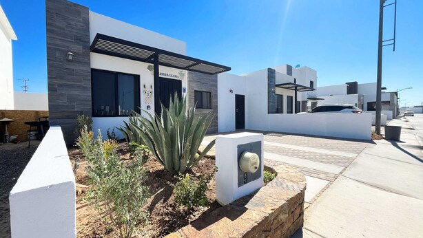 Un bâtiment moderne avec une enseigne indiquant « CASITA LLAMA » et un bac en pierre contenant un cactus.