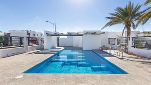 Une piscine à l’eau d’un bleu cristallin, entourée de murs blancs et agrémentée d’un palmier.