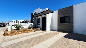 Un bâtiment moderne avec une façade blanche, une porte noire et une petite fenêtre.