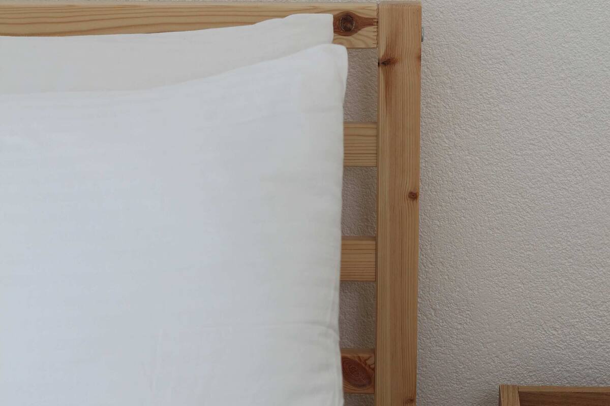 Una cama con cabecera de madera y almohada blanca.