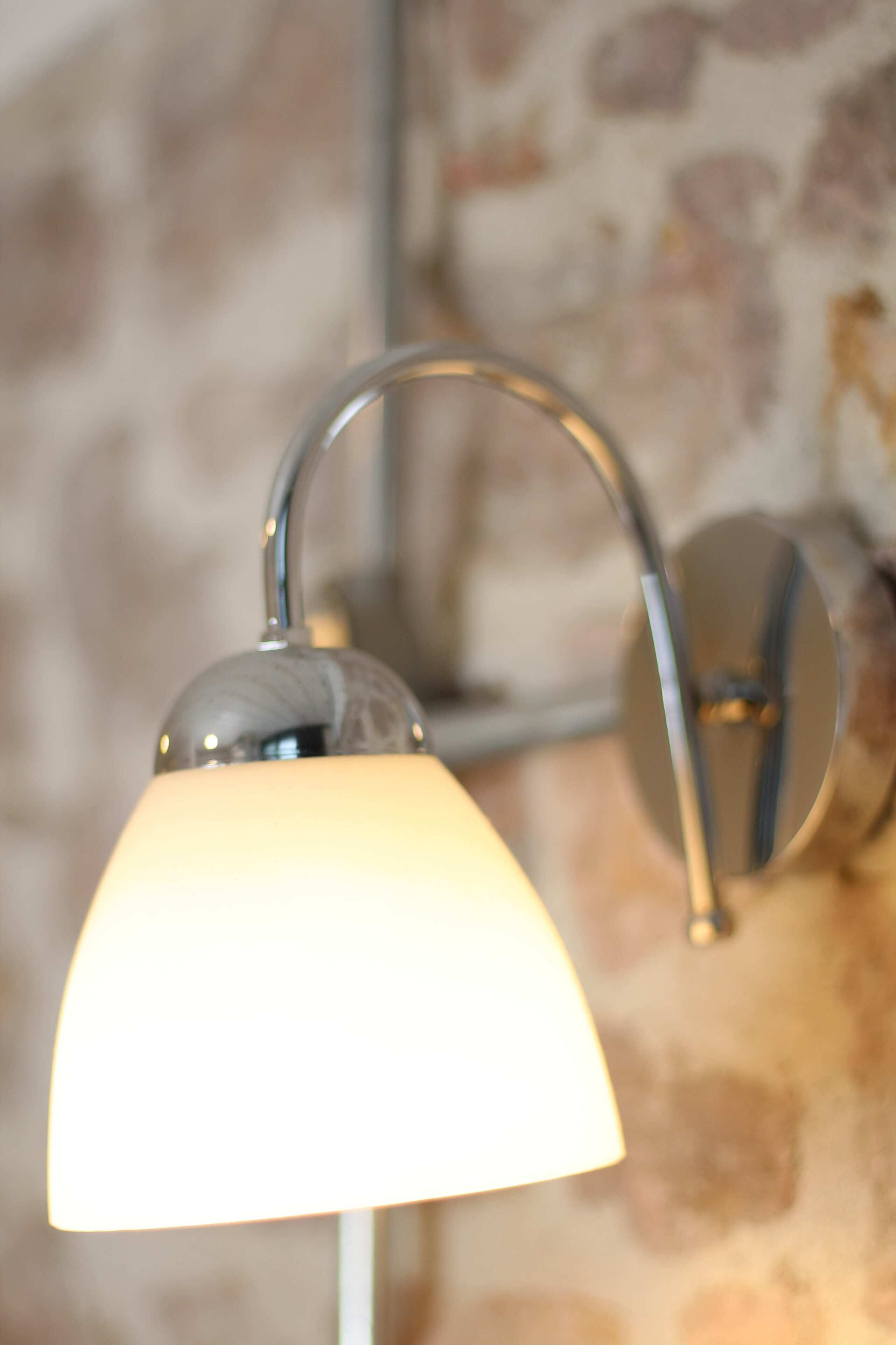 A wall-mounted lamp with a metallic finish and a white shade.