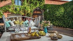 An outdoor seating area with a rustic metal bench, a table set with wine glasses, a bottle, and a vase with flowers. - Linera 10, Emma Villas (Linera)