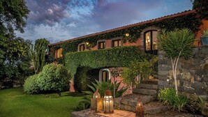 A house with a stone staircase, a covered entrance, and a garden with various plants and decorative lanterns. - Linera 10, Emma Villas (Linera)