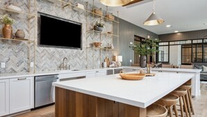 Una cucina moderna con una grande isola, elettrodomestici integrati e una parete di fondo con decorazione a spina di pesce.