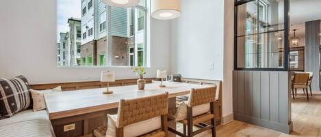 A modern kitchen with a large island, wooden chairs, and a view of neighboring buildings.