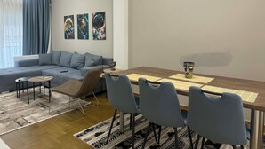 Een moderne woonkamer met een bank, een eettafel met stoelen en kunst aan de muur.
