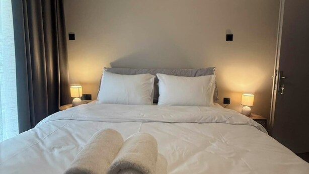 Een hotelkamer met een net opgemaakt bed, twee bedlampen en een deur.