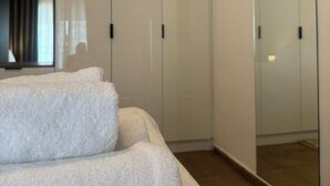 Een moderne slaapkamer met een grote kledingkast, een glazen kast en een grote spiegel.