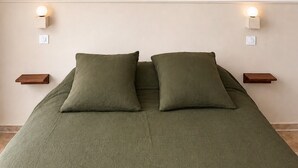 Ein Schlafzimmer mit einem Bett, zwei Nachttischen, einer Hängeleuchte und Wandlampen.