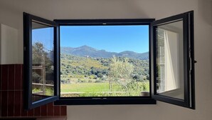 Ein Zimmer mit einem großen Fenster, das einen Blick auf eine grüne Landschaft und Berge bietet.