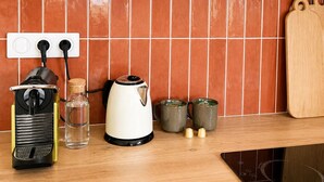 Eine Küche mit Herd, Wasserkocher und elektrischem Wasserkocher auf der Arbeitsplatte, einer gefliesten Spritzschutzwand und Holzschneidebrettern.