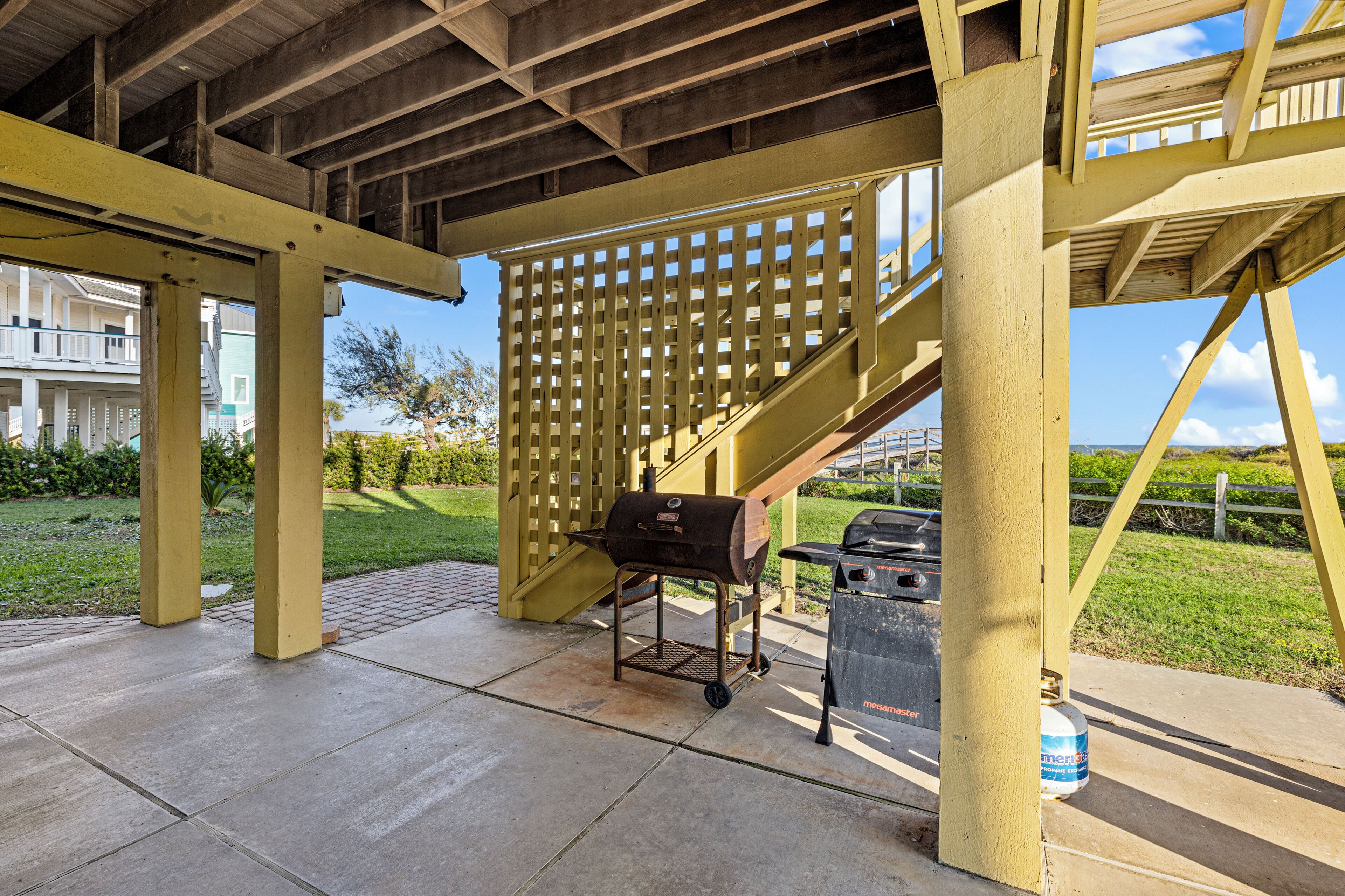 Un patio extérieur couvert, équipé d’un barbecue, d’une poubelle et d’un distributeur d’eau.