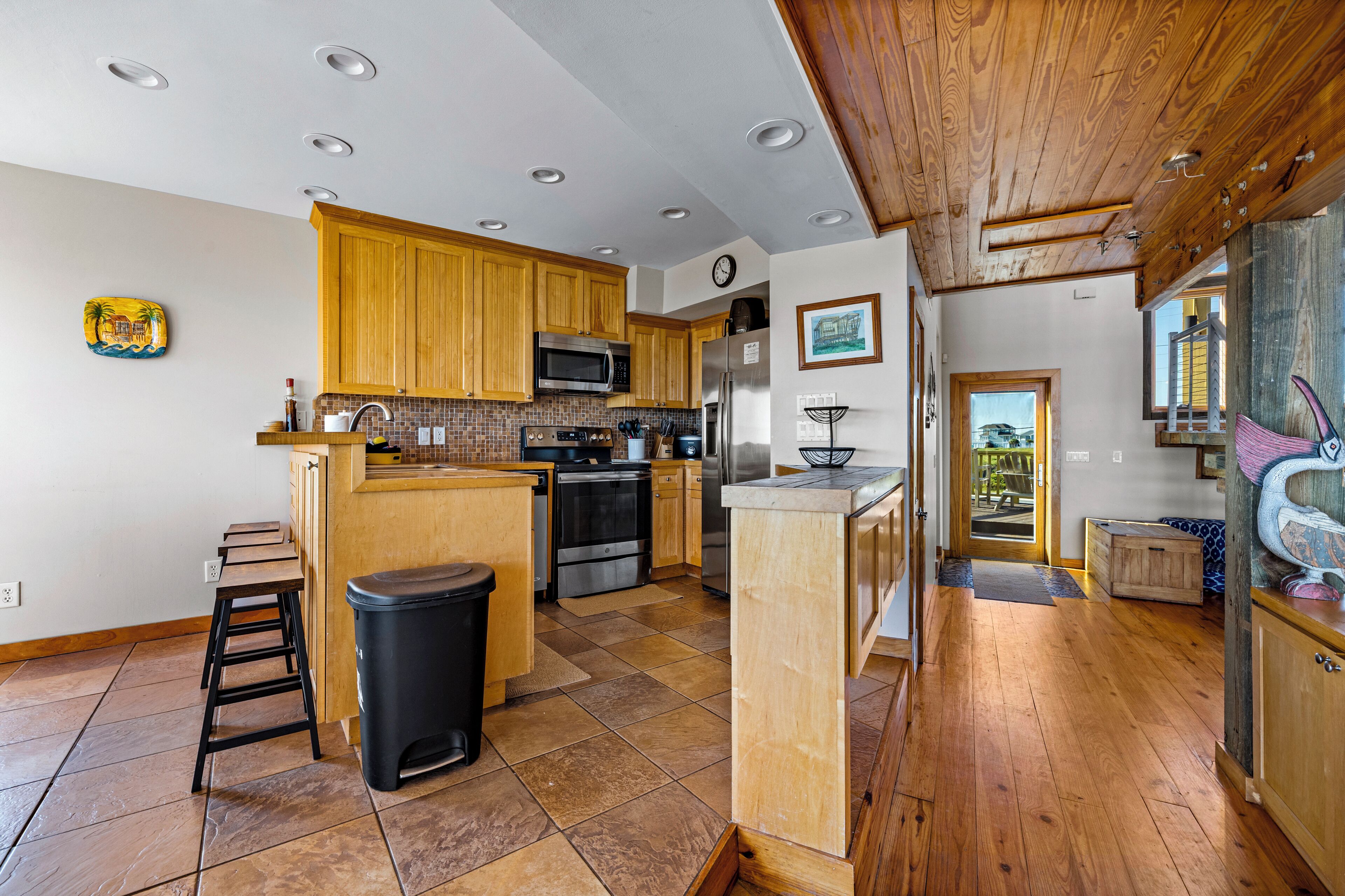 A kitchen with wooden cabinets, a stainless steel refrigerator, and a microwave.