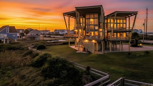 A two-story building with a balcony and a deck, surrounded by a grassy area and other houses. - Villa Seamone (Galveston)
